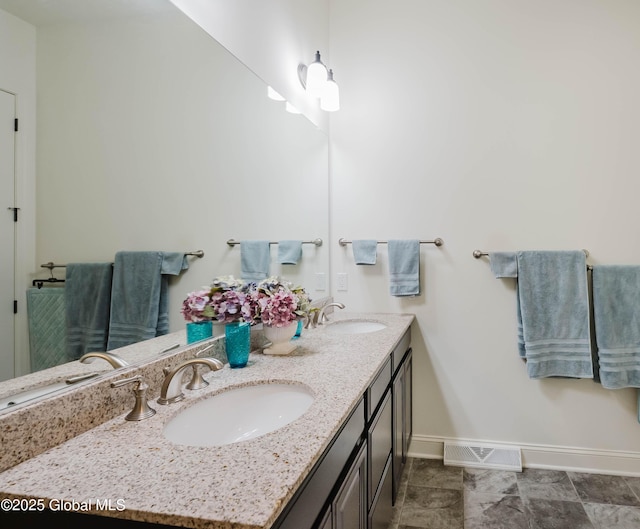 bathroom featuring double vanity, visible vents, baseboards, and a sink