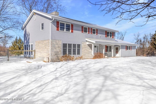 view of front of house featuring stone siding, a chimney, and fence