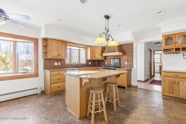 kitchen featuring a baseboard radiator, backsplash, premium range hood, a kitchen bar, and a sink