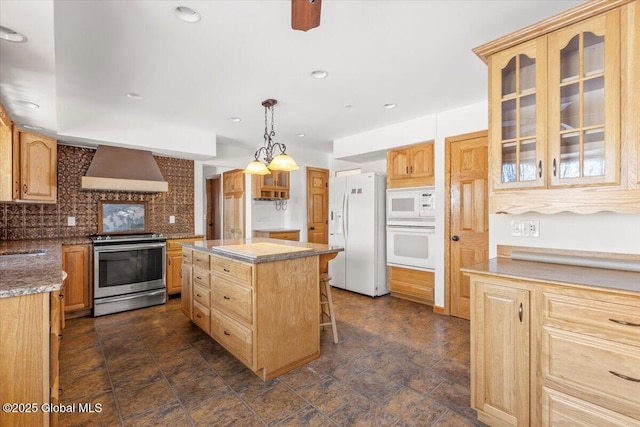 kitchen featuring a center island, tasteful backsplash, a sink, white appliances, and wall chimney exhaust hood