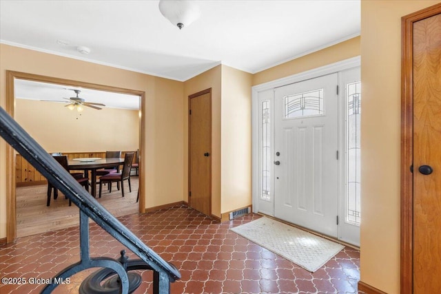 foyer featuring dark floors, ornamental molding, visible vents, and baseboards