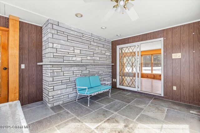 unfurnished room featuring ornamental molding, wood walls, stone tile flooring, and a ceiling fan