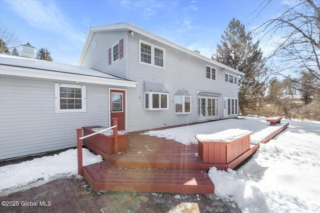 snow covered property with a wooden deck and french doors