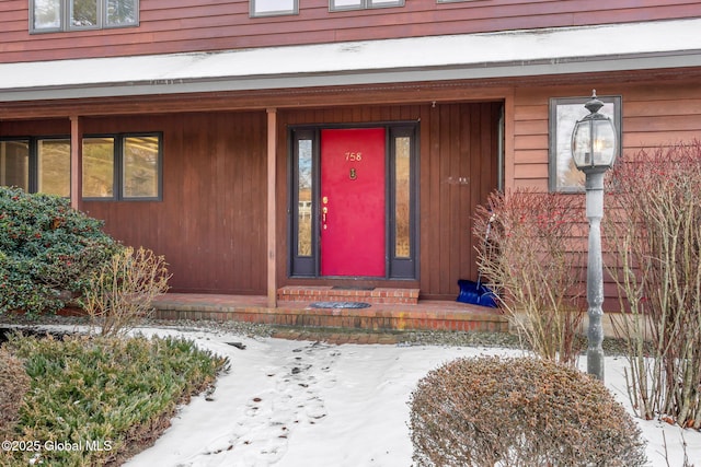 snow covered property entrance featuring a porch