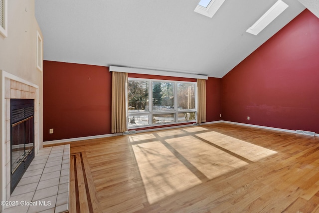 unfurnished living room featuring a skylight, wood finished floors, visible vents, and high vaulted ceiling