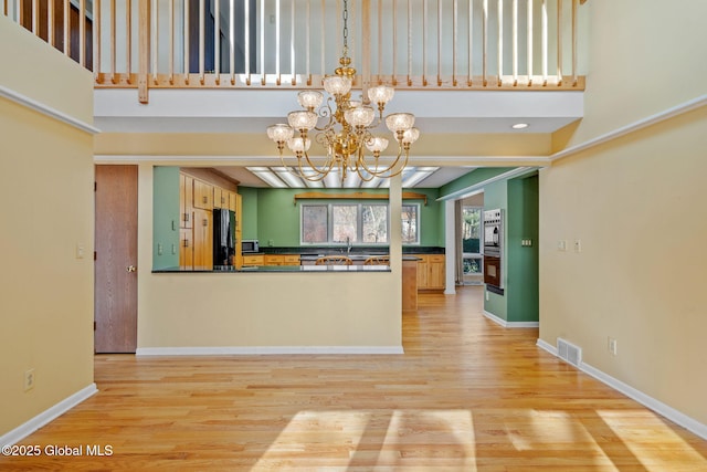 kitchen featuring light wood-style floors, visible vents, dark countertops, and freestanding refrigerator