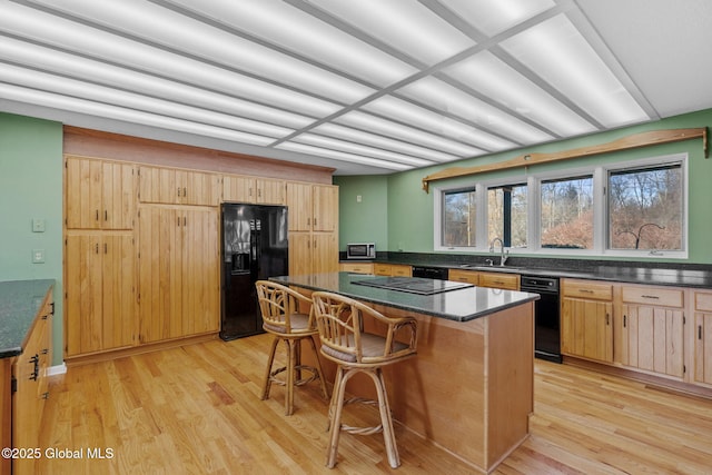 kitchen featuring a sink, dark countertops, light wood-style floors, and black refrigerator with ice dispenser