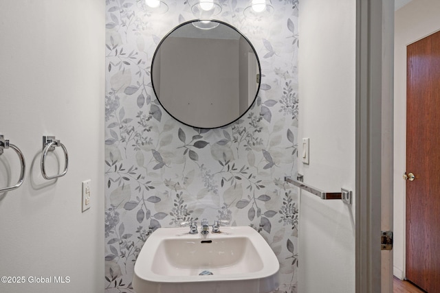 half bathroom with wallpapered walls and a sink