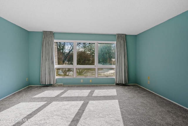 spare room featuring a textured ceiling, baseboards, and carpet