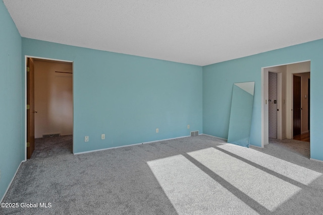 unfurnished bedroom featuring a walk in closet, visible vents, and carpet flooring