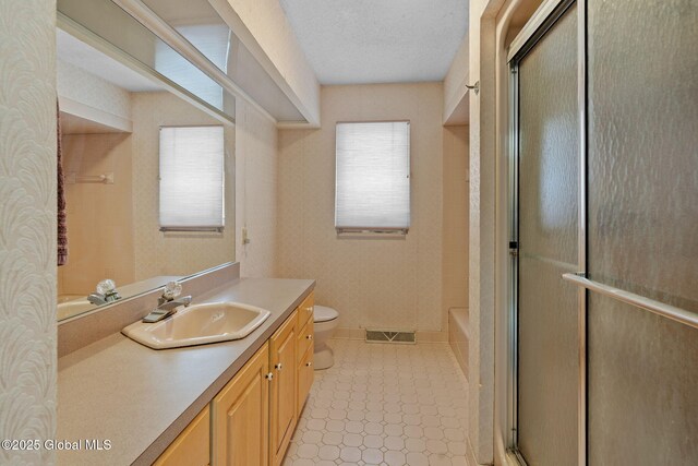 bathroom featuring visible vents, toilet, vanity, an enclosed shower, and a textured ceiling