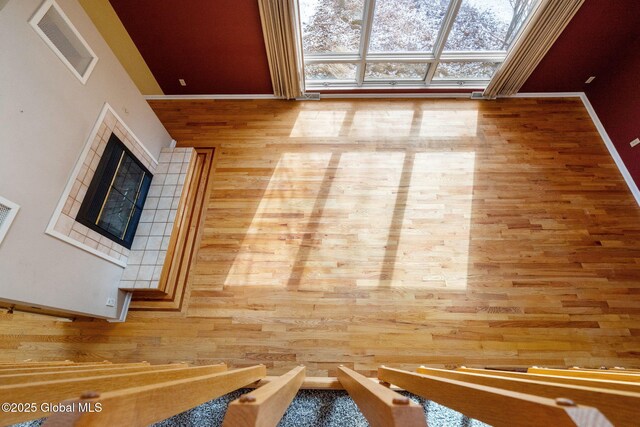 interior space featuring baseboards, wood finished floors, visible vents, and a tile fireplace