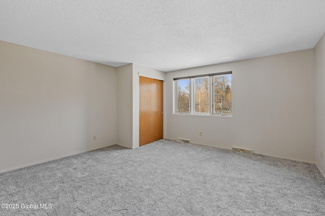 unfurnished bedroom with visible vents, carpet, a closet, and a textured ceiling