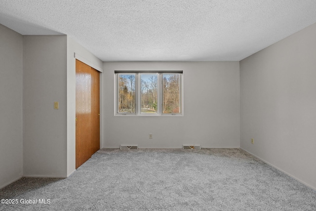 spare room with visible vents, carpet flooring, and a textured ceiling