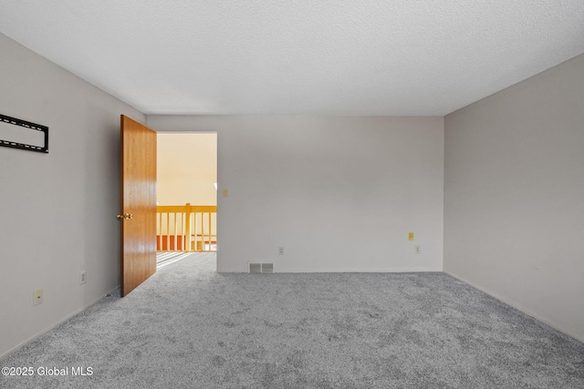 carpeted spare room featuring visible vents and a textured ceiling