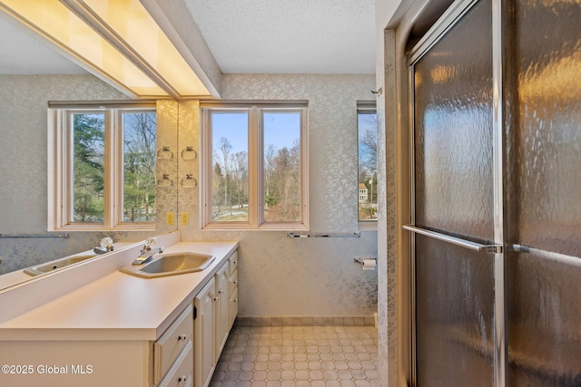 bathroom with vanity, wallpapered walls, baseboards, and a textured ceiling