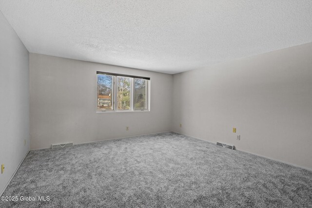 carpeted spare room with visible vents and a textured ceiling