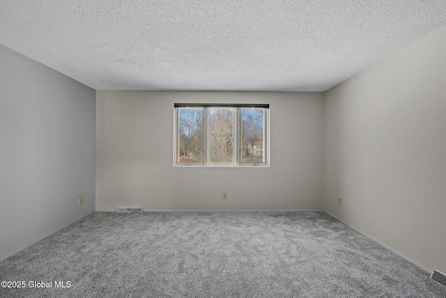 unfurnished room featuring visible vents, carpet floors, and a textured ceiling