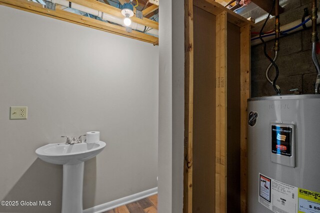 bathroom with baseboards, electric water heater, and wood finished floors