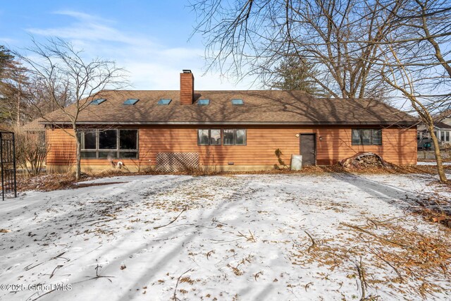 snow covered back of property with a chimney and a shingled roof