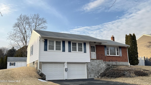 single story home featuring an outbuilding, aphalt driveway, an attached garage, brick siding, and a chimney