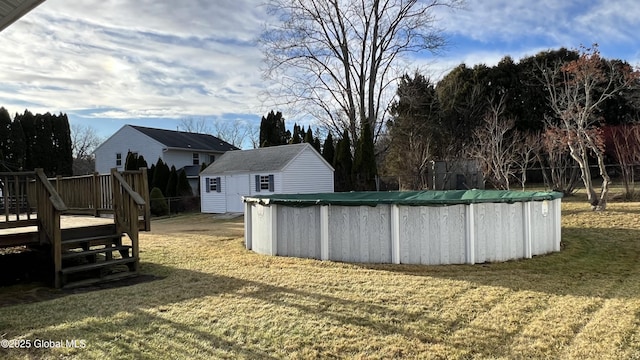 view of yard featuring a covered pool, a shed, a deck, and an outbuilding