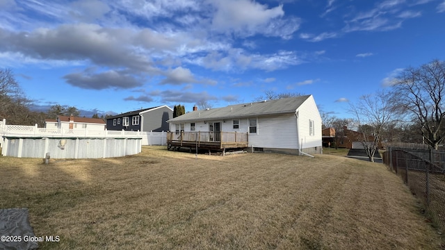 back of property featuring a lawn, a wooden deck, a fenced in pool, and a fenced backyard