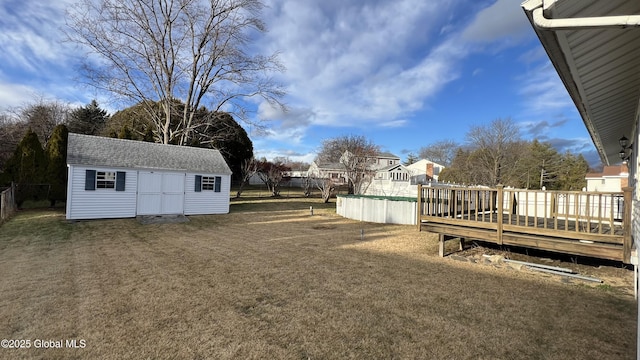 view of yard with an outbuilding, fence, a deck, and a shed