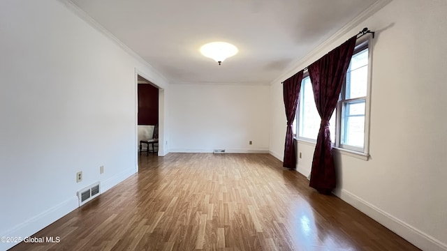 unfurnished room featuring visible vents, crown molding, baseboards, and wood finished floors