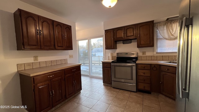 kitchen with stainless steel appliances, light countertops, dark brown cabinets, and light tile patterned floors