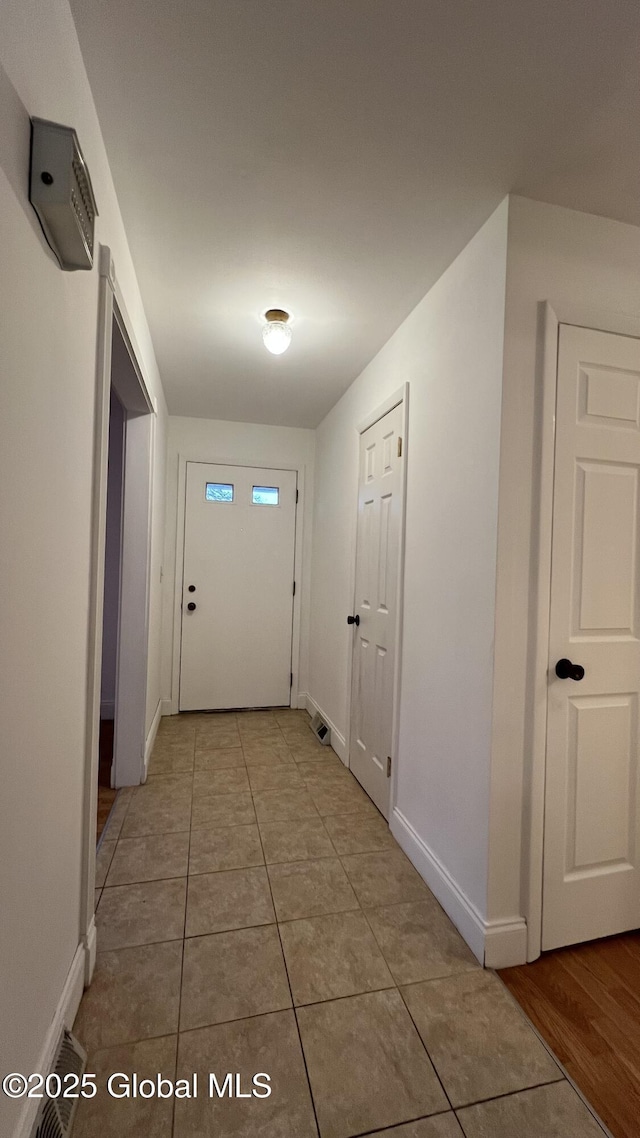 doorway featuring light tile patterned floors and baseboards