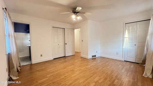 unfurnished bedroom featuring baseboards, ensuite bathroom, visible vents, and light wood-style floors