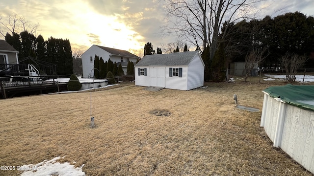 yard at dusk with a fenced in pool, an outdoor structure, a shed, and fence