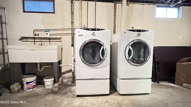 clothes washing area with laundry area, separate washer and dryer, and a sink