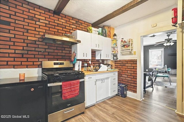 kitchen featuring range hood, stainless steel gas stove, brick wall, and beam ceiling