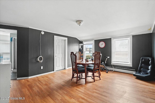 dining room featuring a baseboard heating unit, baseboards, wood finished floors, and ornamental molding