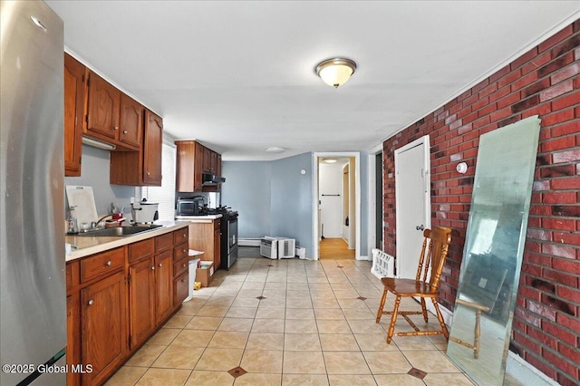 kitchen featuring a sink, freestanding refrigerator, range with gas cooktop, brick wall, and light countertops