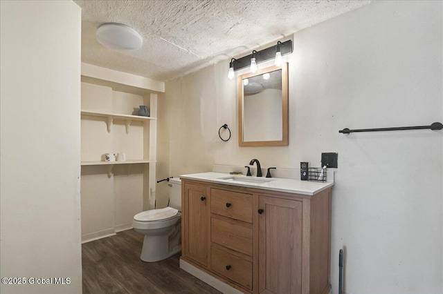 bathroom featuring vanity, toilet, wood finished floors, and a textured ceiling