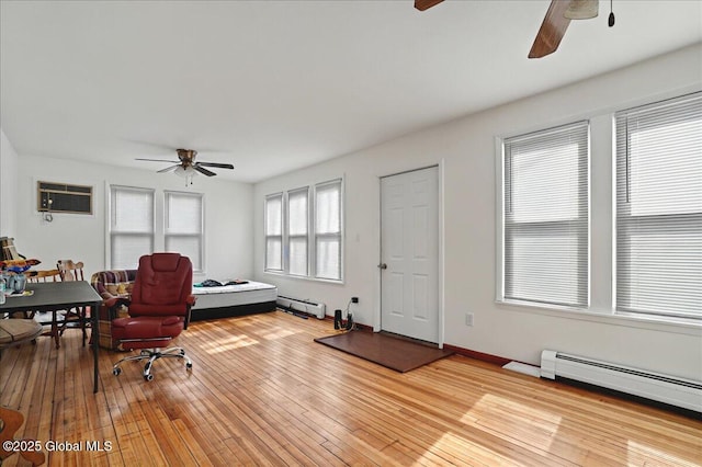 office space featuring a baseboard heating unit, baseboard heating, ceiling fan, and hardwood / wood-style flooring