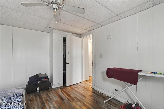 misc room with a drop ceiling, a ceiling fan, and wood finished floors