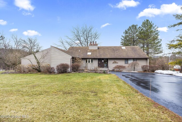 ranch-style home with driveway, a chimney, and a front yard