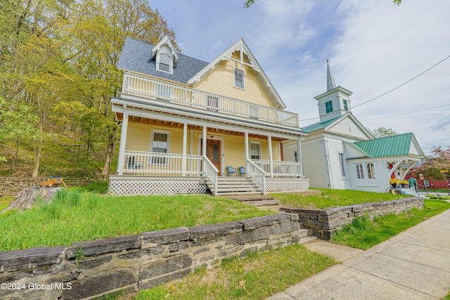 victorian home with a balcony, a porch, and a front yard