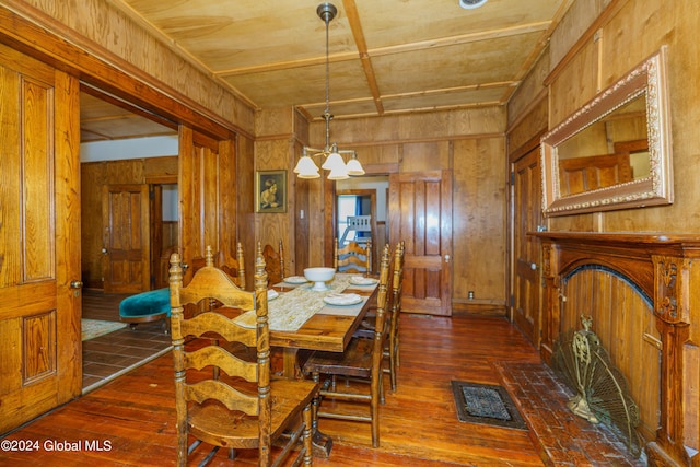 dining room with a chandelier, dark wood-style flooring, visible vents, and wooden walls