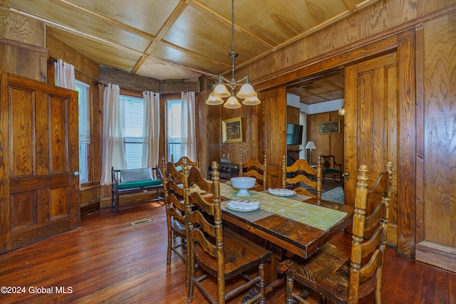 dining room with a notable chandelier, wooden walls, visible vents, and dark wood-style flooring