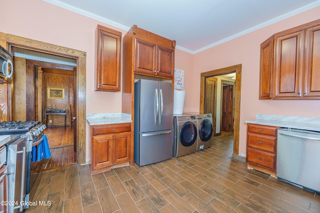 kitchen featuring appliances with stainless steel finishes, ornamental molding, light countertops, washer and dryer, and wood finish floors