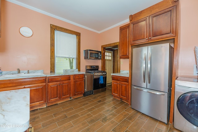 kitchen featuring stainless steel appliances, a sink, wood tiled floor, washer / dryer, and crown molding