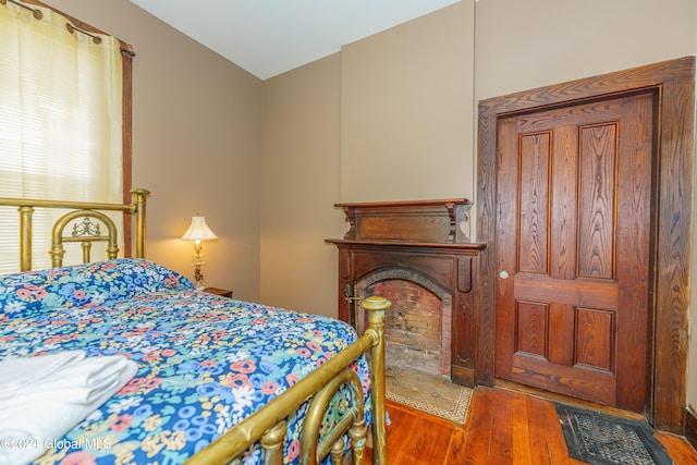 bedroom with a fireplace with flush hearth and wood finished floors