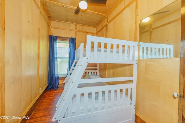 bedroom featuring wood walls, baseboards, and wood finished floors