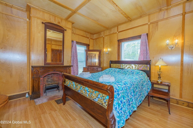 bedroom featuring a fireplace with flush hearth, baseboards, wood finished floors, and wooden walls