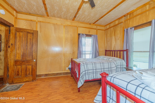 bedroom with wooden ceiling, light wood finished floors, and wood walls